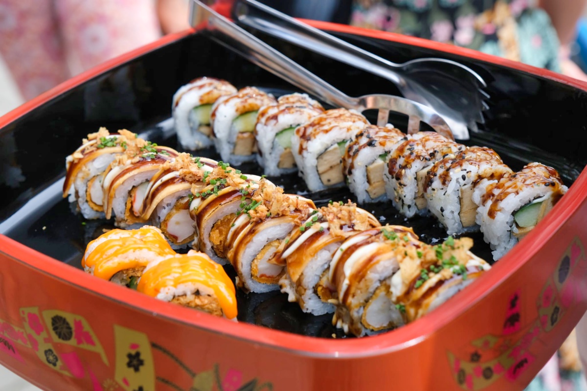 In a red Japanese tray, you see all the beautifully cut sushi rolls. There by a pair of tongs with which you can pick up the sushi.