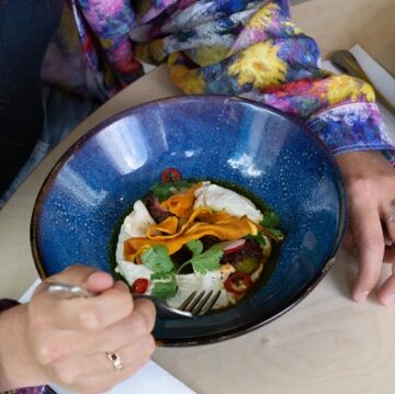 Een hand om een blauw bord met een wit oranje gerecht