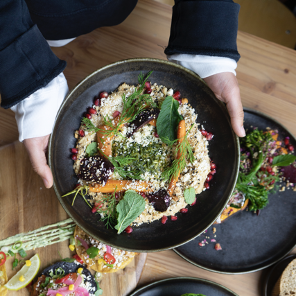 Handen houden een bord pindahummus vast