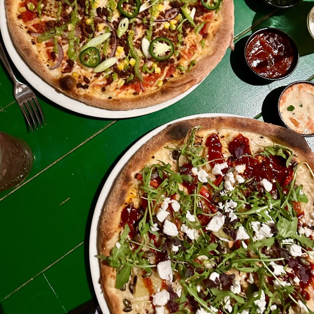 Een groene tafel met pizza's