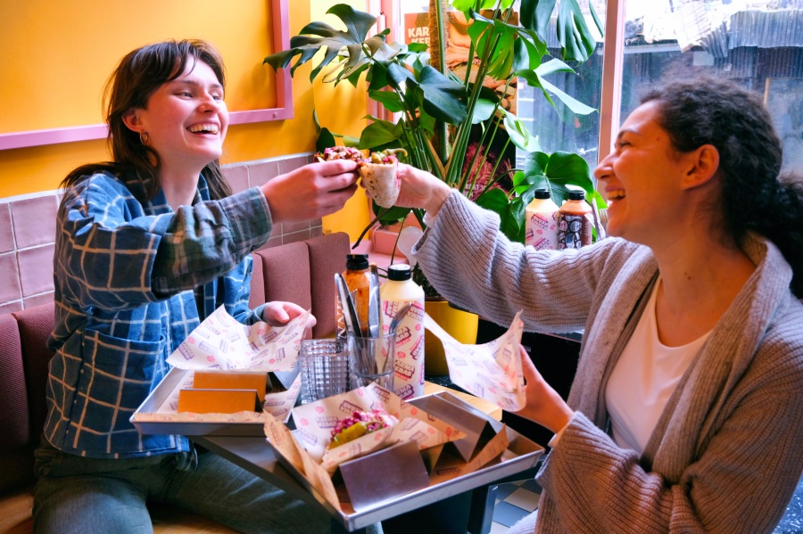 Twee dames die proosten met een broodje kebab tijdens een teamuitje in Amsterdam.